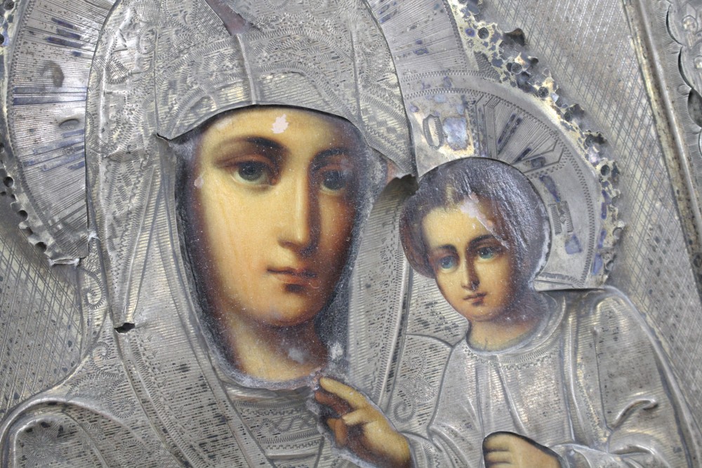 A Russian white metal overlaid tempera on panel icon, depicting the Virgin Mary and Christ child, 22 x 18cm